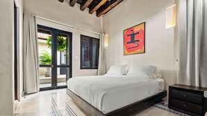 Un dormitorio con cama, mesita de noche, puerta y ventana.