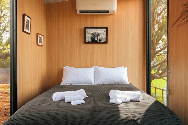 Una habitación de hotel con una cama grande, almohadas blancas y un cuadro de un toro en la pared.