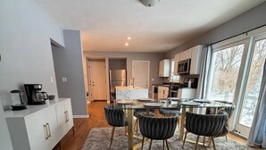 Une cuisine moderne avec un coin repas, un plancher en bois et une vue dégagée grâce à de grandes fenêtres.