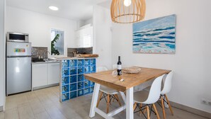 Una cocina moderna con armarios blancos, una mesa de comedor de madera y un mueble de almacenamiento azul.