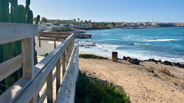Un muelle de madera con vista a una playa y al océano.
