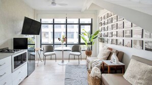 Un saló modern amb cuina, zona de menjador i una finestra gran amb vistes a la ciutat.