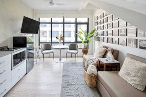 Ein modernes Wohnzimmer mit Küche, Essbereich und einem großen Fenster mit Blick auf die Stadt.