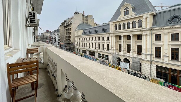 A balcony with a row of wooden chairs and a white railing. - Bucharest Little Paris Elegance (București)