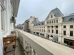 A balcony with a row of wooden chairs and a white railing. - Bucharest Little Paris Elegance (București)