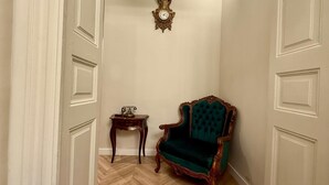 A narrow hallway with a green upholstered chair and a small wooden table with a vintage telephone. - Bucharest Little Paris Elegance (București)
