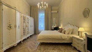 Une chambre à coucher avec un grand lit, une commode, un miroir et un lustre.