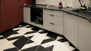 A modern kitchen with a black and white patterned floor, a built-in dishwasher, and a stainless steel sink. - Bucharest Little Paris Elegance (București)