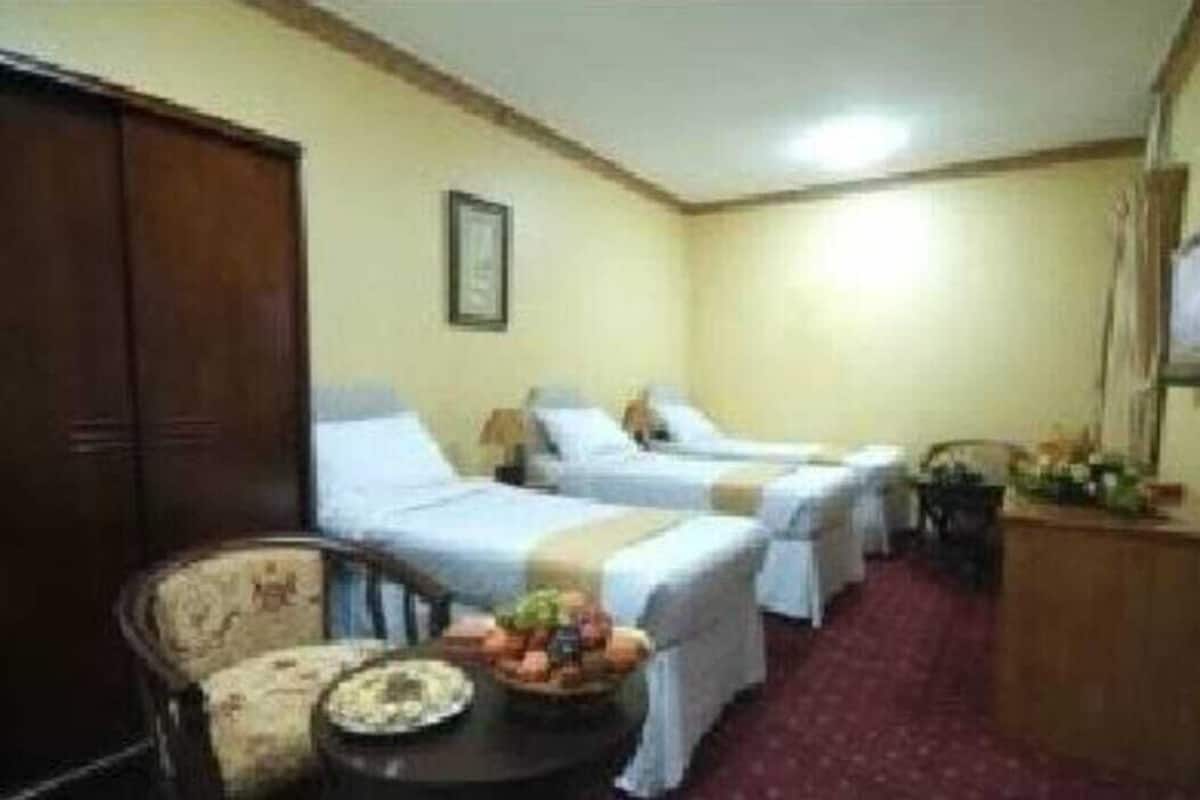 Een hotelkamer met twee enkele bedden, een houten kast, een tafeltje met fruit en een stoel.
