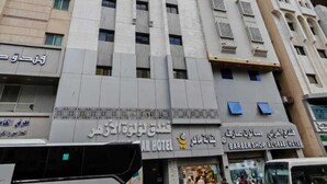 Un hôtel à plusieurs étages doté d’une façade moderne, avec un bar et un salon de coiffure situés au rez-de-chaussée.