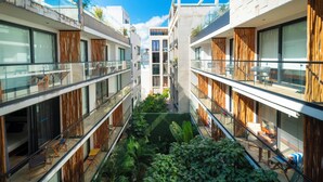 A modern apartment building with multiple balconies, large windows, and a central courtyard with greenery. - 2 BR Condo with Rooftop Pool - Sasha II (Playa del Carmen)