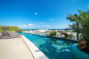 A swimming pool with lounge chairs and a view of the ocean. - 2 BR Condo with Rooftop Pool - Sasha II (Playa del Carmen)