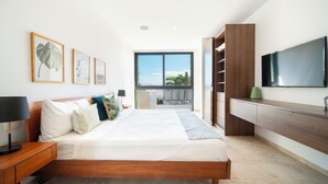 A modern bedroom with a large bed, a TV, and a balcony with a view. - 2 BR Condo with Rooftop Pool - Sasha II (Playa del Carmen)