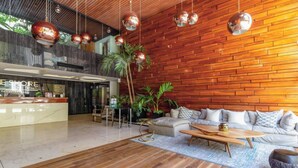 A modern lobby with a wooden wall, a reception desk, a sofa, and a coffee table. - 2 BR Condo with Rooftop Pool - Sasha II (Playa del Carmen)