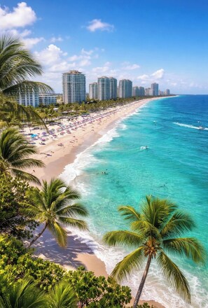 A beach with clear turquoise waters, palm trees, and a row of high-rise hotels in the background. - 5BR West Palm Beach Getaway with Fenced Yard, Pets Welcome (West Palm Beach)