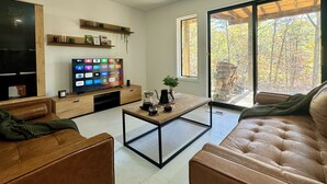 Un saló modern amb un televisor pla gran, prestatges de fusta, una taula de centre i un sofà.