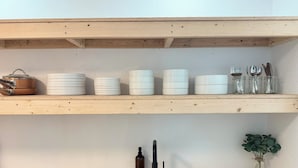 Cuina amb un rentaplat de color negre, una cuina i prestatges amb recipients i envasos de vidre blancs.