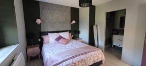 Ein Schlafzimmer mit einem Bett, Nachttischen, einer Kommode, einem Spiegel und einer Wand mit Muster.
