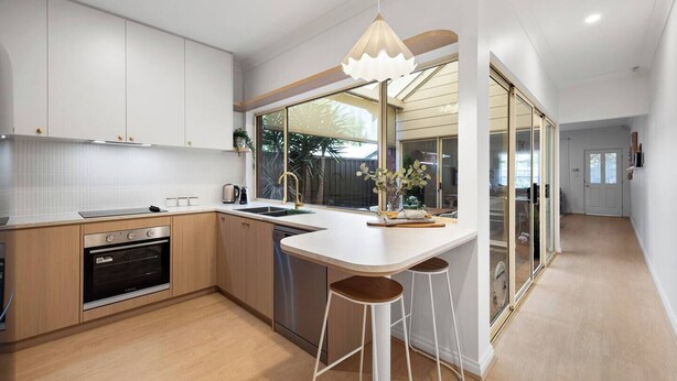 Cocina moderna con una isla central, horno empotrado y un amplio ventanal.
