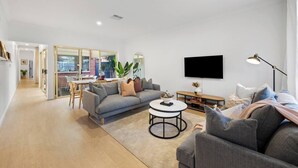 Una sala moderna con un sofá gris, una mesa de centro y un televisor montado en la pared.