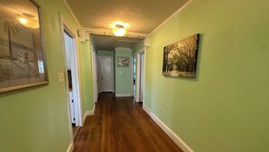 Un corridoio con pareti verdi, pavimento in legno e una lampada a soffitto.