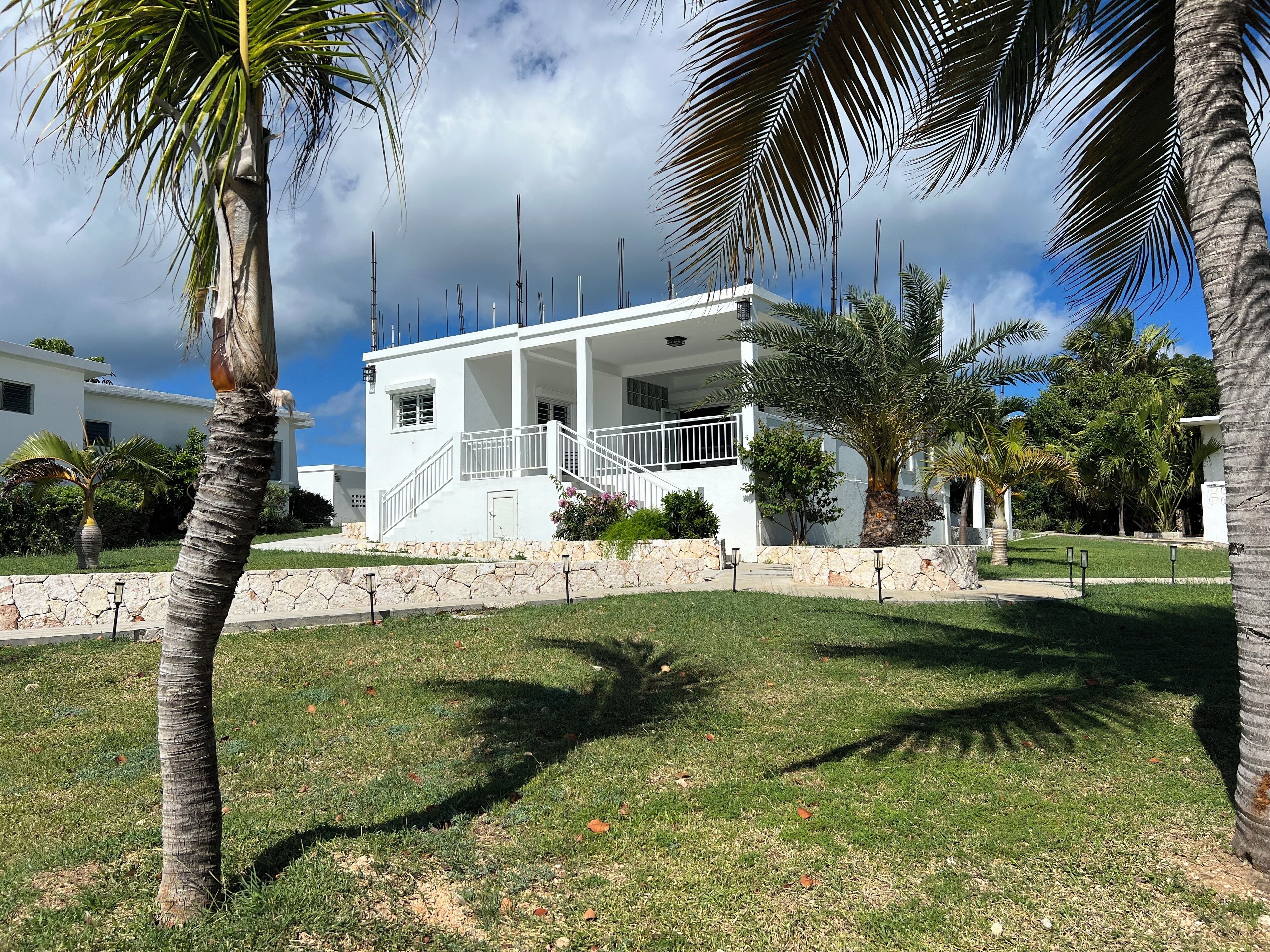 A white building with a stone wall and a grassy lawn.