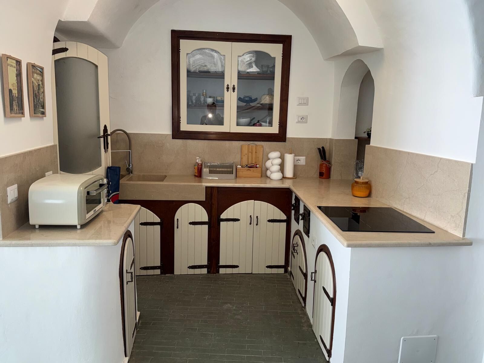A compact kitchen with a built-in oven, a sink, and a window above the cabinets.