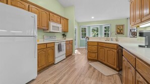 Une cuisine avec des meubles en bois, un réfrigérateur blanc, un four à micro-ondes et une cuisinière.