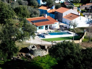 Une maison avec une piscine, entourée d’arbres et d’un mur de pierre.