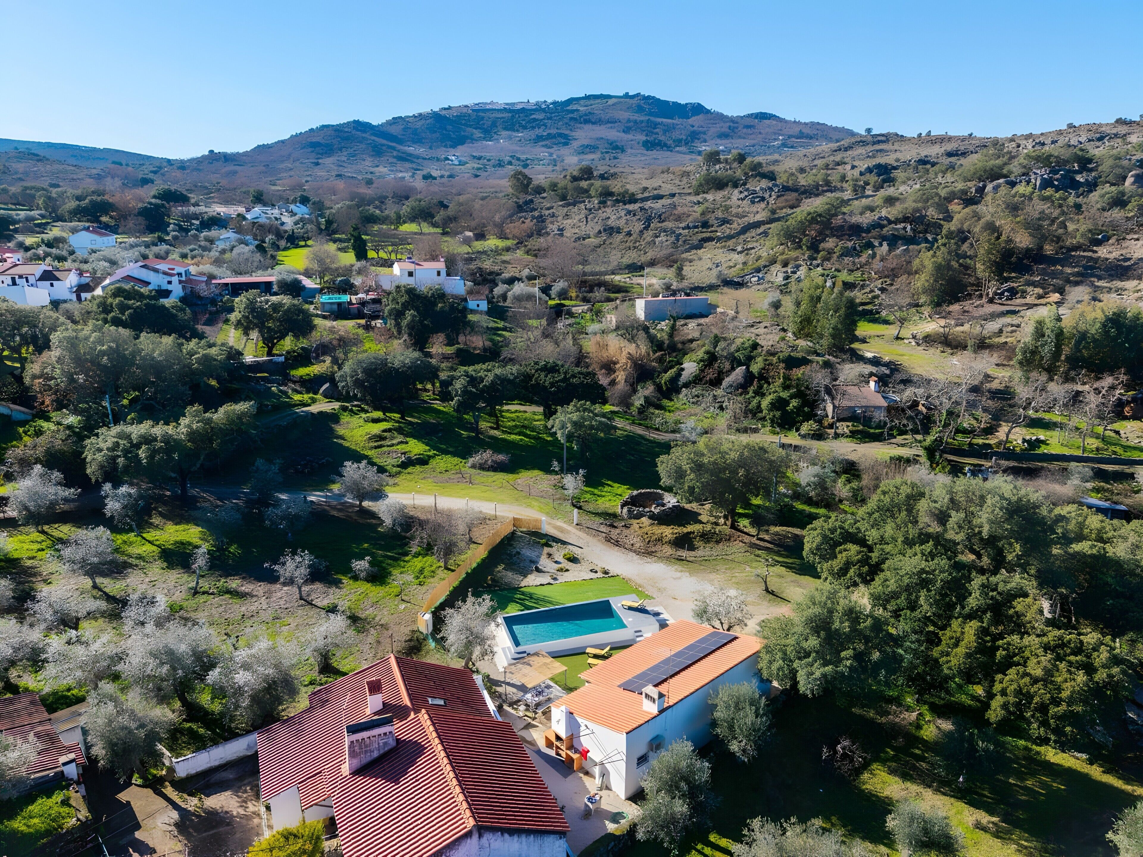 Vista aérea de una zona residencial con casas, una piscina y un paisaje montañoso al fondo.