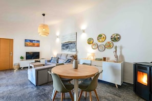 Un salon moderne comprenant un canapé, un téléviseur, une table à manger, des chaises et une cheminée.