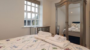 A bedroom with a bed, a large mirror, a window with a view, and a bedside table. - The Lodge House (Lancaster)