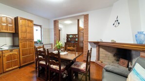 A kitchen with wooden cabinets, a dining table with chairs, a fireplace, and a blue vase on a mantel. - Casa Terra Mia - Two Bedroom House, Sleeps 4 (Cabras)