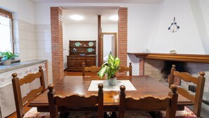 A dining area with a wooden table, chairs, a potted plant, and a brick fireplace. - Casa Terra Mia - Two Bedroom House, Sleeps 4 (Cabras)