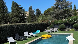 A rectangular swimming pool with clear blue water, surrounded by a well-manicured lawn and various trees. - VILLA M, Swimming pool, Beach on foot (La Croix-Valmer)
