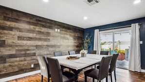 Un comedor con pared de madera, una mesa grande y sillas.