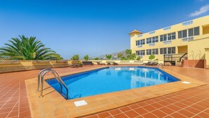 A swimming pool with a tiled deck, a metal ladder, and lounge chairs. - Vacation Apartment 'Balcones Del Atlantico' with Sea View, Shared Pool and Wi-Fi (Playa de las Américas)