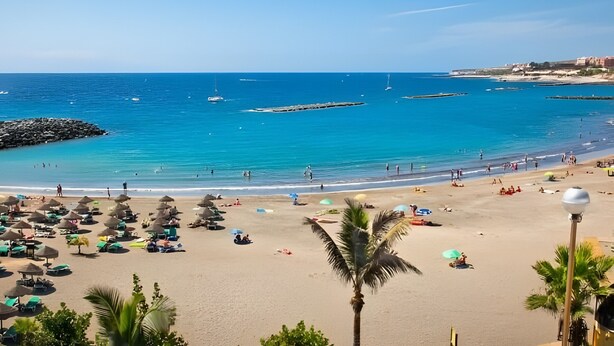 A beach with umbrellas, sun loungers, and a clear blue sea. - Vacation Apartment 'Balcones Del Atlantico' with Sea View, Shared Pool and Wi-Fi (Playa de las Américas)