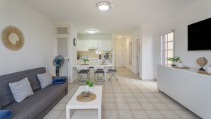 A modern living room with a sofa, coffee table, and a dining area with chairs and a table. - Vacation Apartment 'Balcones Del Atlantico' with Sea View, Shared Pool and Wi-Fi (Playa de las Américas)