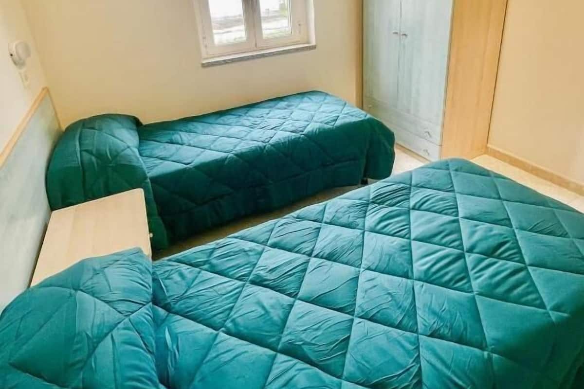 A room with two single beds, a window, and a wardrobe.
