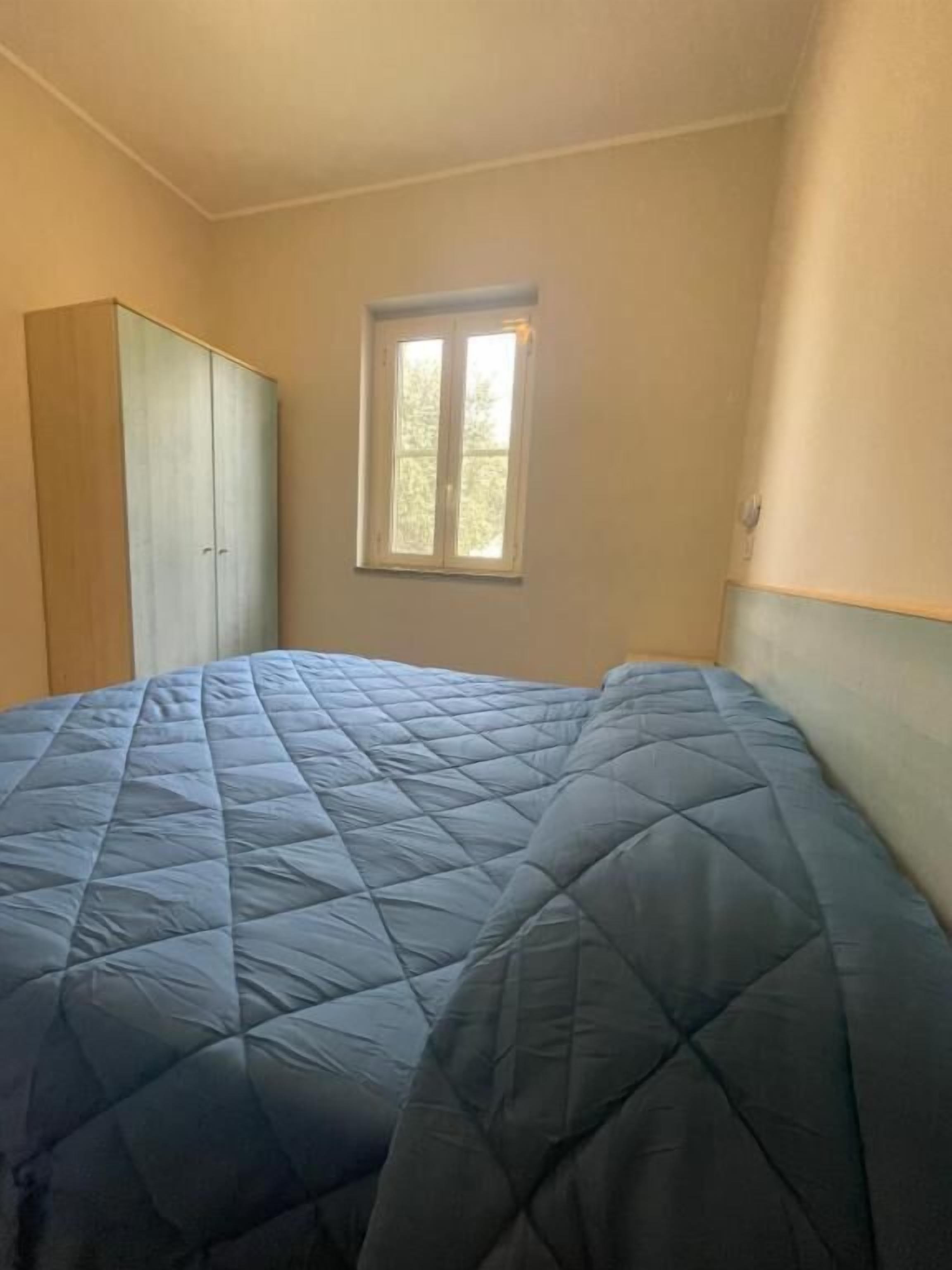 A bedroom with a bed, a wardrobe, and a window.