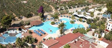 An aerial view of a resort with multiple swimming pools, sun loungers, and palm trees.