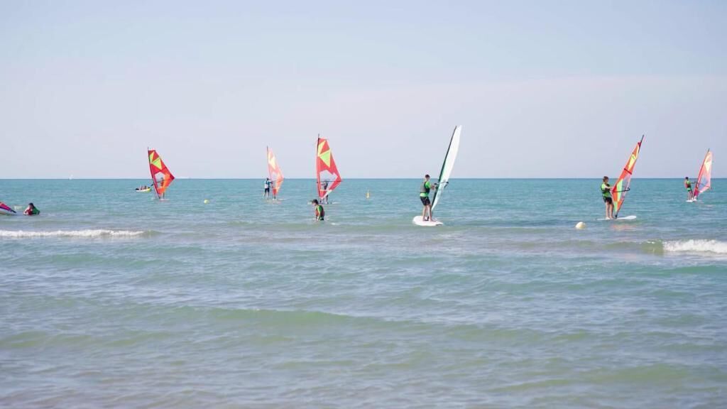 A beach with people windsurfing.