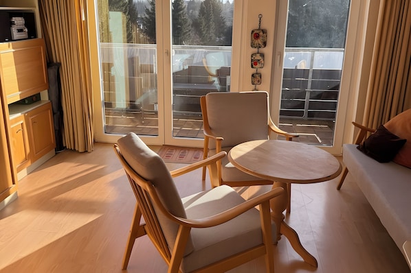 Ein Zimmer mit einem Holzkabinett, einer Couch, einem runden Tisch und Stühlen.