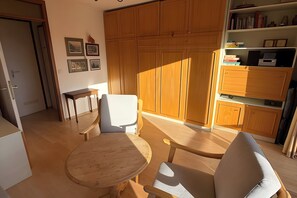 Ein Zimmer mit Holzschnitzschränken, einem Bücherregal, einem Esstisch mit Stühlen und gerahmten Bildern an der Wand.