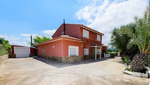 Een huis met twee verdiepingen, een rode gevel, een stenen fundering en een garage.