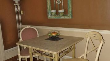 A dining area with a wooden table and two chairs, a decorative window, and a floor lamp.