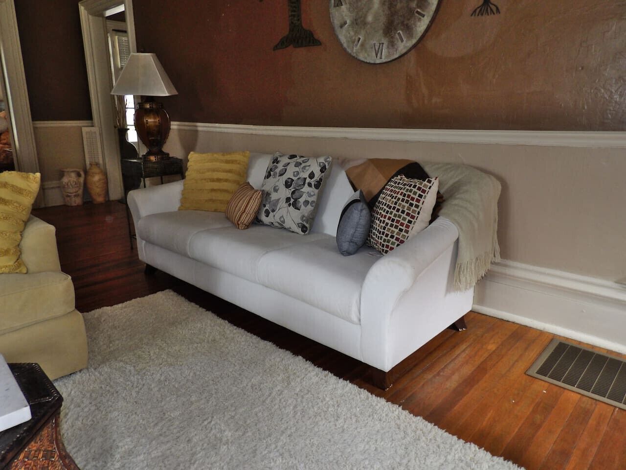 A living room with a white sofa, a white rug, and a wooden floor.
