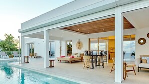 Ein modernes Haus mit Schwimmbad, offener Terrasse und Essbereich.