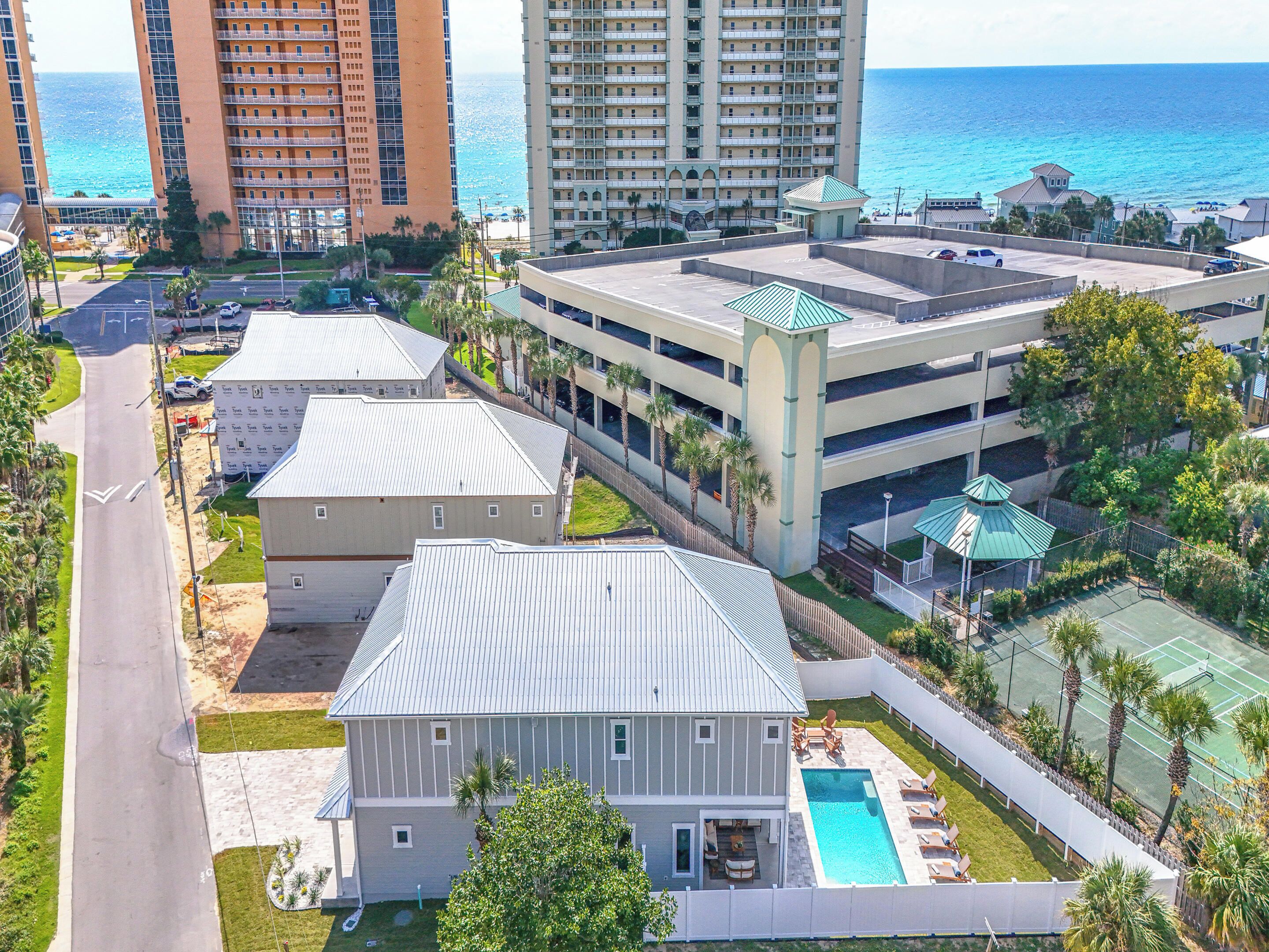 Una zona residenziale con piscina, campo da tennis e vista sull'oceano.